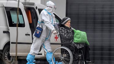 Medical worker wearing personal protective equipment (PPE) pushes a patient in a wheel chair towards the entrance of a hospital in Kommunarka outside Moscow on November 16, 2020, amid the ongoing Covid-19 pandemic. (AFP)