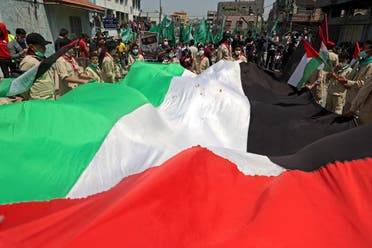 Palestinian protesters wave national (foreground) and Hamas movement flags during a demonstration in the Jabalia refugee camp in the Gaza Strip on April 30, 2021, following the postponement of the upcoming Palestinian elections. (AFP)