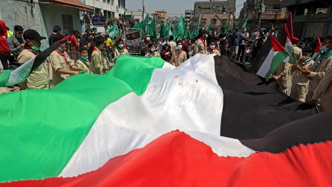 Palestinian protesters wave national (foreground) and Hamas movement flags during a demonstration in the Jabalia refugee camp in the Gaza Strip on April 30, 2021, following the postponement of the upcoming Palestinian elections which were supposed to take place next month. (AFP)