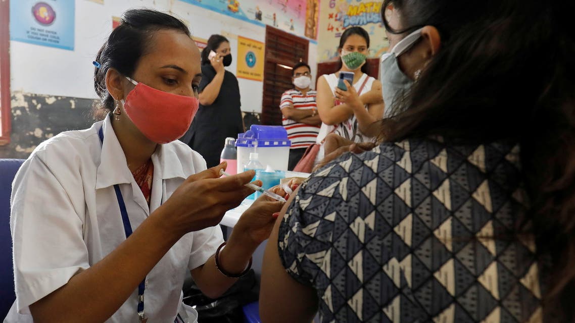 A healthcare worker gives a dose of COVISHIELD, a coronavirus disease (COVID-19) vaccine manufactured by Serum Institute of India, to a woman inside a classroom of a school, which has been converted into a temporary vaccination centre, in Ahmedabad, India, May 1, 2021. (Reuters)