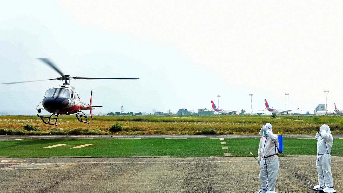 Members of ground staff wearing protective gear stand near a helicopter transporting a Covid-19 coronavirus patient at the Tribhuvan International Airport in Kathmandu on May 3, 2021. (File photo: AFP)