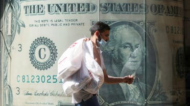 A man wearing a protective face mask walks in front of a currency exchange bureau advertisement showing an image of the U.S. dollar amid the coronavirus disease (COVID-19) pandemic in Cairo, Egypt May 5, 2021. (File photo: Reuters)