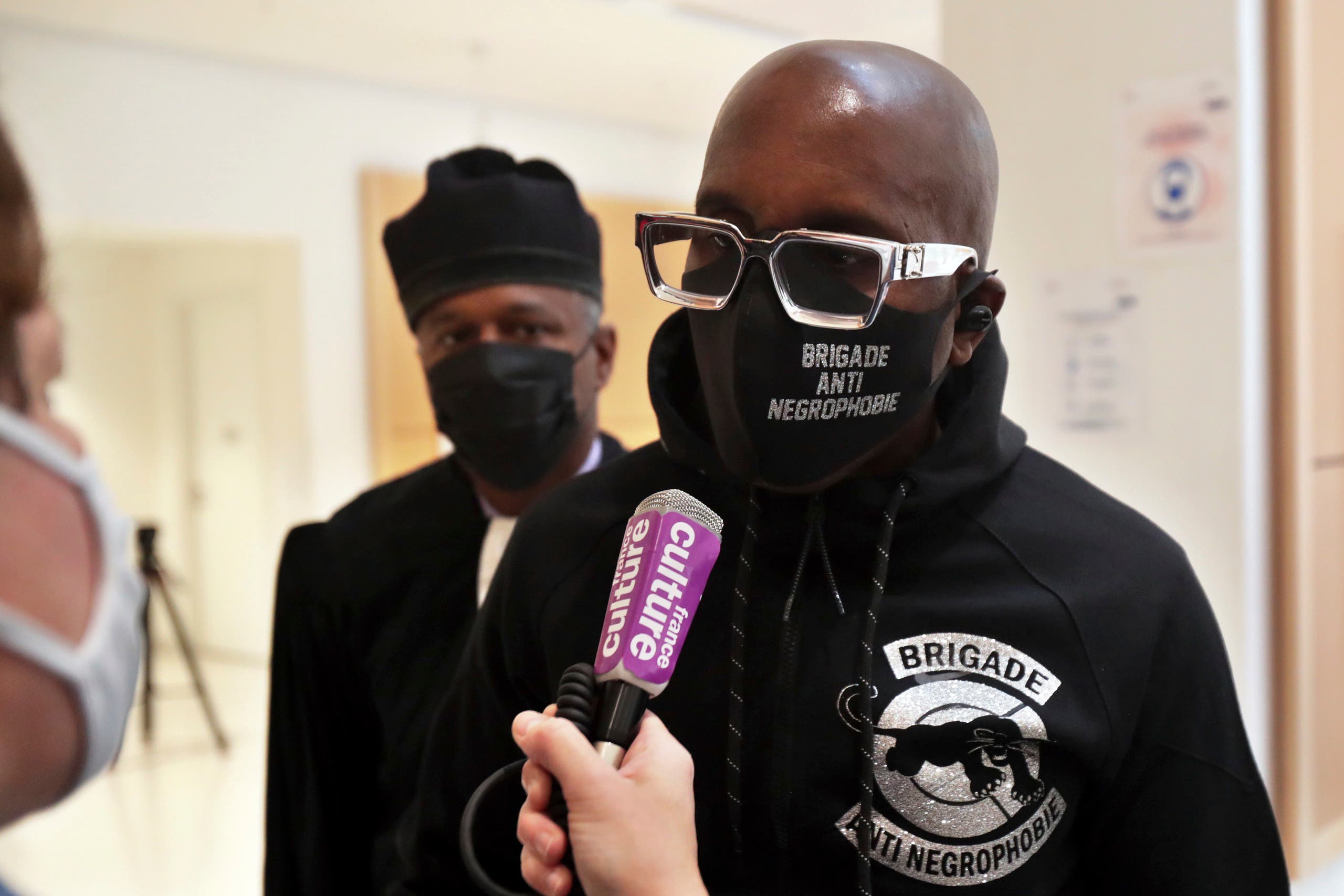 An activist from a group called the Anti-Negrophobia Brigade, Franco Lollia, wears a face mask reading Anti-Negrophobia Brigade as he talks to media at the Paris courthouse, in Paris, May 10, 2021. (AP)