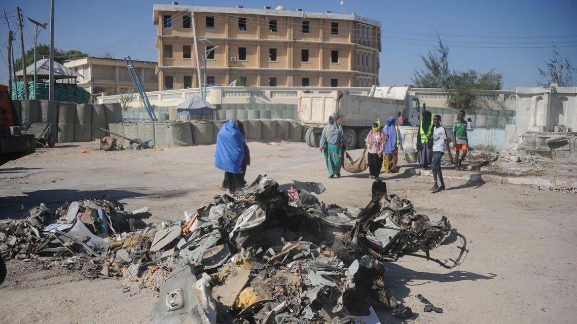 People walk near the wreckage of a car near the complex housing Somalia’s ministries of works and labor stormed by al-Shabab militants in Mogadishu. (File photo: AFP)