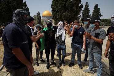 Palestinians stand together as the Dome of the Rock is seen in the background following clashes with Israeli police at the compound that houses al-Aqsa Mosque in Jerusalem’s Old City on May 10, 2021.  (Reuters)