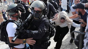 A Palestinian woman runs near Israeli security force members during scuffles amid Israeli-Palestinian tension as Israel marks Jerusalem Day, at Damascus Gate just outside Jerusalem’s Old City on May 10, 2021. (Reuters)