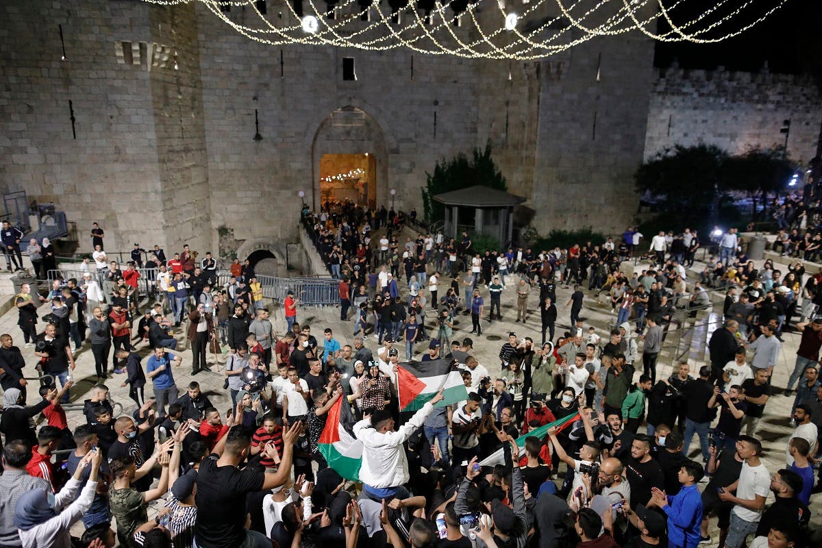 Palestinian protesters raise national flags as they gather near the Damascus Gate in Jerusalem's Old City, on April 25, 2021. (AFP)
