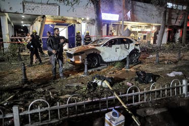 Israeli security and civil defense forces stand by a damaged vehicle in Holon near Tel Aviv, on May 11, 2021, after rockets were launched from the Gaza Strip. (Ahmad Gharabli/AFP)