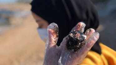 Volunteer holding tar balls at Tyre. (Image: Hussein Ghaddar)
