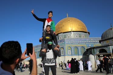 Palestinian youths pose as a friend photographs them, while the Dome of the Rock is seen in the background, during Eid al-Fitr prayers, which mark the end of the holy fasting month of Ramadan, at the compound that houses al-Aqsa mosque on May 13, 2021. (Reuters)