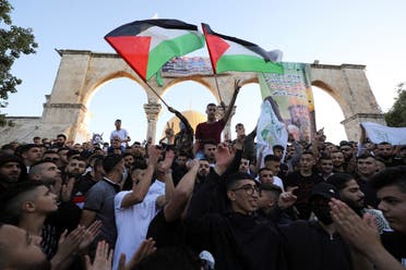 People wave Palestinian flags during Eid al-Fitr prayers, which mark the end of the holy fasting month of Ramadan, at the compound that houses al-Aqsa mosque on May 13, 2021. (Reuters)