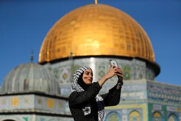 A Palestinian woman takes a selfie as the Dome of the Rock is seen in the background, during Eid al-Fitr prayers on May 13, 2021. (Reuters)