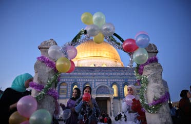 Muslim women blow up balloons as worshippers celebrated the Eid al-Fitr holiday, which marks the end of the holy fasting month of Ramadan, after the morning prayer at the al-Aqsa mosques compound, with the Dome of the Rock mosque in the background, in Old Jerusalem early on May 13, 2021. (AFP)