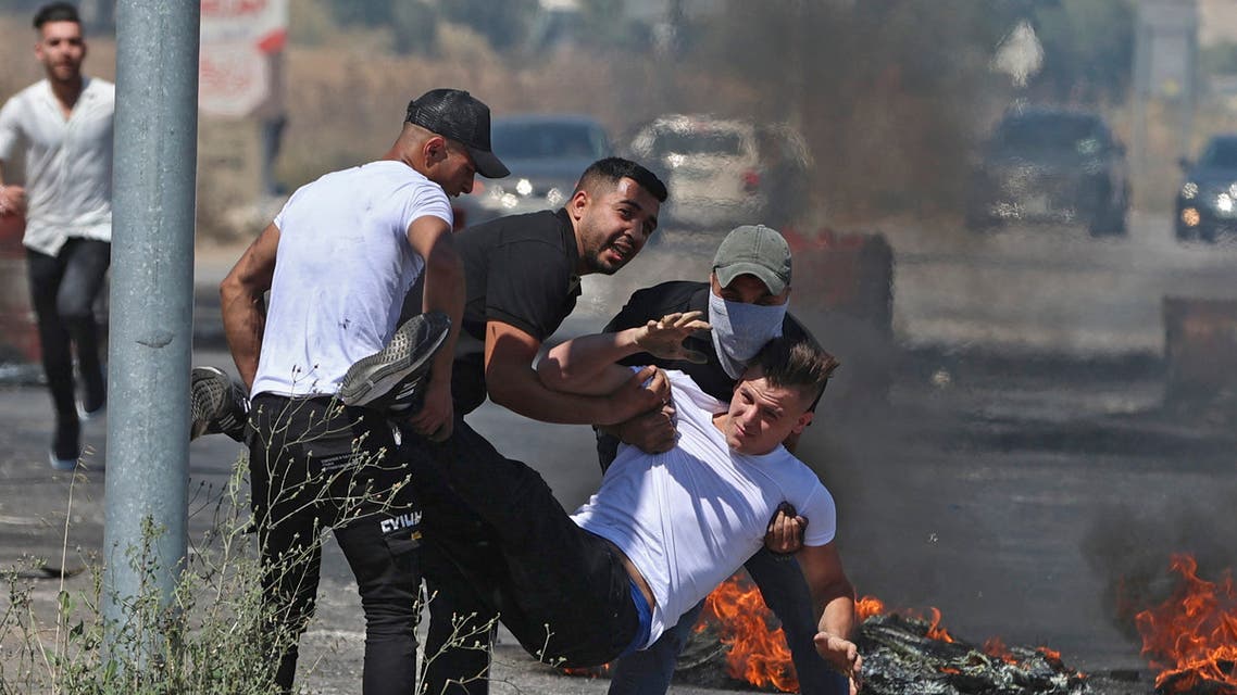 Palestinians carry an injured man to safety, during confrontations with Israeli security forces near the Hawara checkpoint south of the occupied West Bank city of Nablus, on May 14, 2021. (AFP)