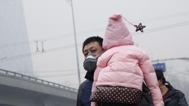 A man wearing a mask carries his baby on his shoulder amid heavy smog after the city issued its first ever red alert for air pollution, in Beijing, China, December 8, 2015. (File photo: Reuters)