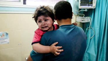 A Palestinian man holds an injured girl awaiting medical care at al-Shifa hospital, after an Israeli air strike in Gaza city, on May 11, 2021. (AFP)