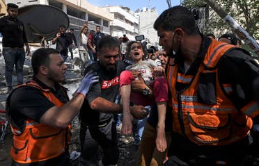 Palestinian paramedics evacuate a girl from the rubble of a destroyed building in Gaza City's Rimal residential district on May 16, 2021, following massive Israeli bombardment. (AFP)