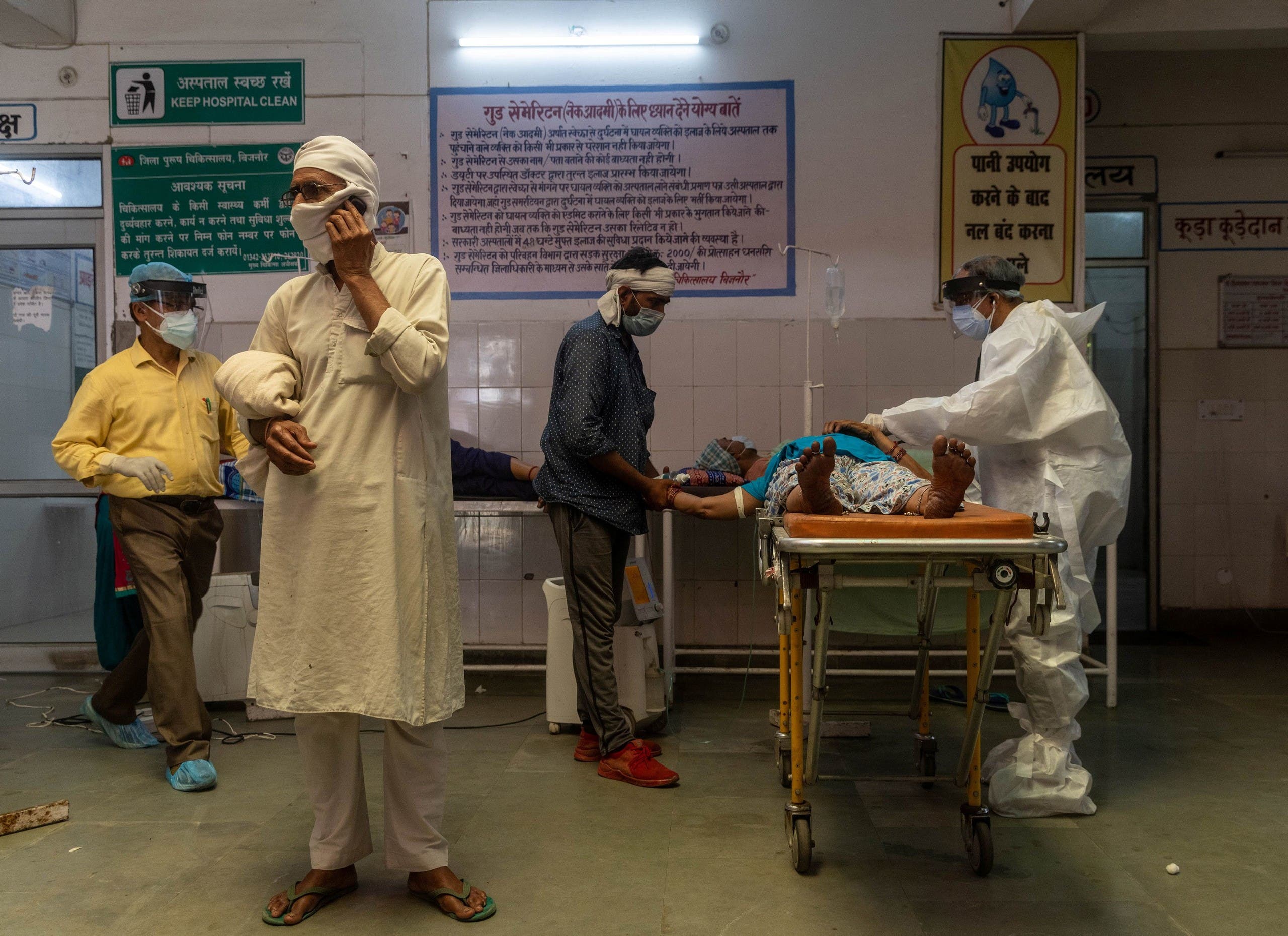 رجل يتحدث على الهاتف بينما تحاول طبيبة في أحد مستشفيات بجنور بالهند انعاش زوجته