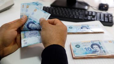 A man counts 10 Dinar banknotes depicting the country's first woman doctor, Tawhida Ben Cheikh, in Tunis, Tunisia. (File photo: Reuters)