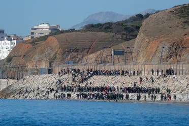 Migrants are led by Moroccan soldiers back to Morocco from El Tarajal beach, at the fence between the Spanish-Moroccan border, after thousands of migrants swam across the border, in Ceuta, Spain, May 19, 2021. (Reuters)