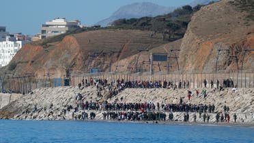 Migrants are led by Moroccan soldiers back to Morocco from El Tarajal beach, at the fence between the Spanish-Moroccan border, after thousands of migrants swam across the border, in Ceuta, Spain, May 19, 2021. (Reuters)