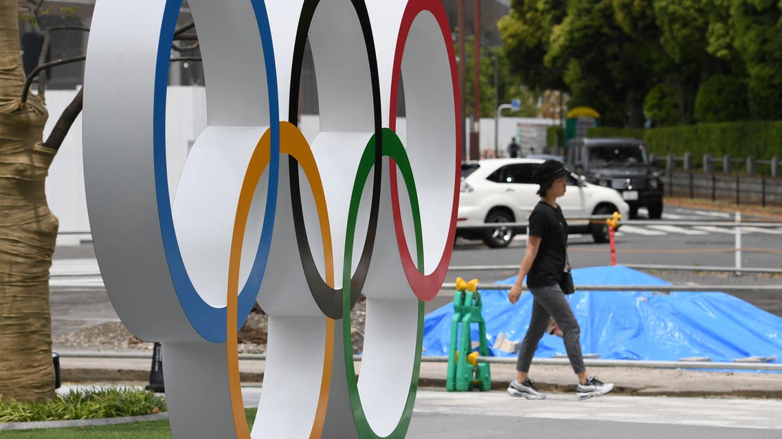 A pedestrian walks beside the Olympic Ring displayed at the Japan Sport Olympic Square beside the under constructing national stadium in Tokyo on May 18, 2019. (File photo: AFP)