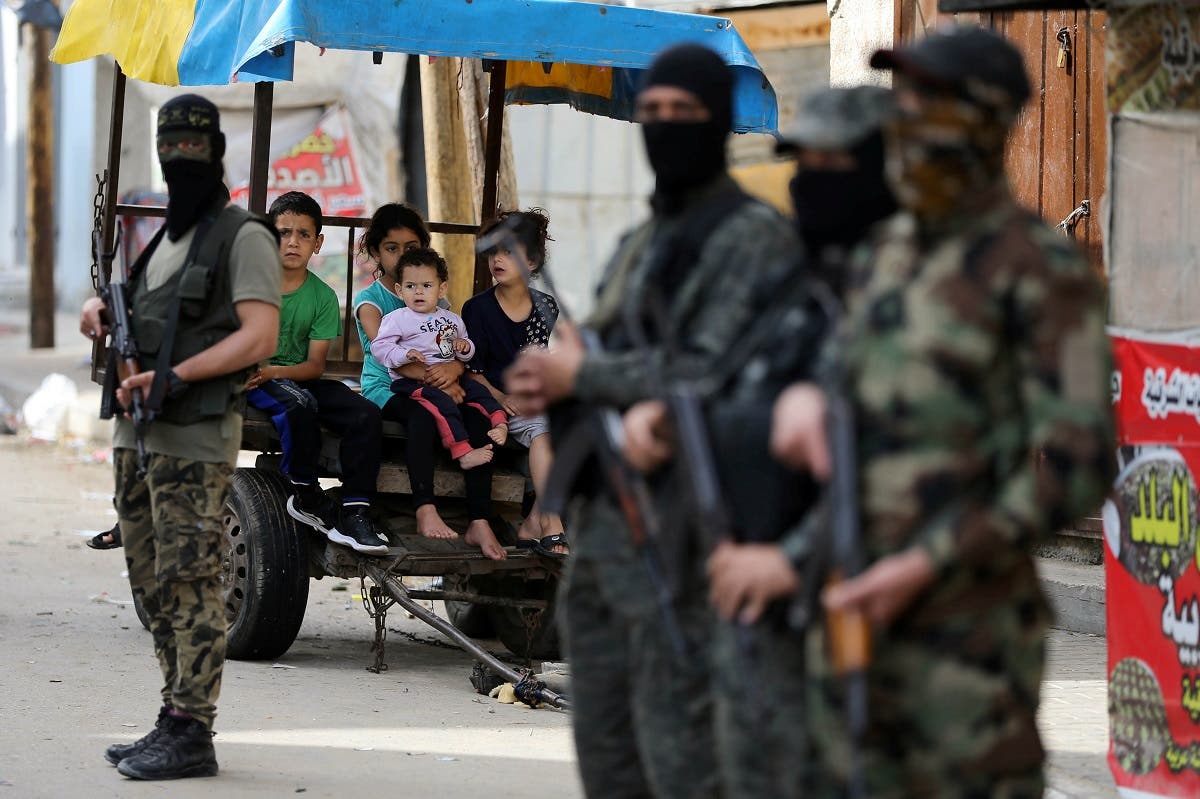 Palestinian children look on as Islamic Jihad militants stand guard following Israel-Hamas truce, in Gaza May 21, 2021. (Reuters)