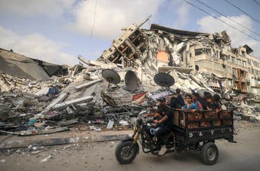 رجل ينقل أطفال في غزة ويمر أمام مبنى هدمه القصف الإسرائيلي