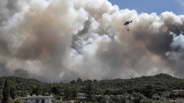 A firefighting helicopter flies over the the village of Alepochori, after an overnight fire on a mountain range overlooking the Gulf of Corinth, on May 20, 2021. (AFP)