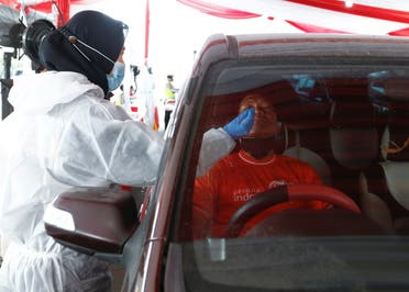 A healthcare worker in personal protective equipment takes a swab sample from a person to be tested for COVID-19 as travellers return to the capital city after the Eid al-Fitr festival, amid the coronavirus disease (COVID-19) pandemic, in Cikarang, Bekasi, on the outskirts of Jakarta, Indonesia, May 17, 2021. (Reuters)