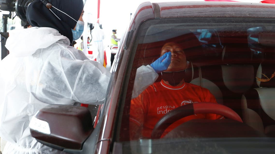 A healthcare worker in personal protective equipment takes a swab sample from a person to be tested for COVID-19 as travellers return to the capital city after the Eid al-Fitr festival, amid the coronavirus disease (COVID-19) pandemic, in Cikarang, Bekasi, on the outskirts of Jakarta, Indonesia, May 17, 2021. (Reuters)