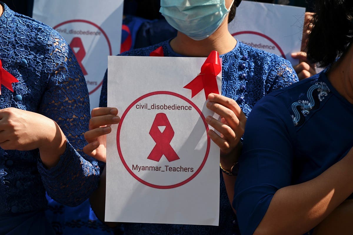 A teacher from Yangon University of Education holds a sign with a red ribbon while taking part in a demonstration against the military coup in Yangon, Myanmar, February 5, 2021. (Reuters)