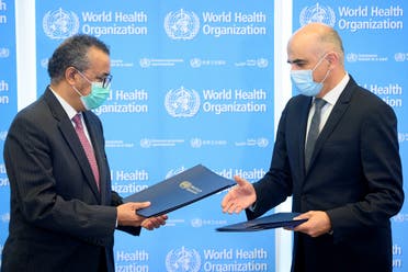 Swiss Interior and Health Minister Alain Berset (R) exchanges documents with World Health Organization (WHO) Director General Tedros Adhanom Ghebreyesus during a bilateral meeting on the sidelines of the opening of the 74th World Health Assembly at the WHO headquarters, in Geneva, Switzerland, on May 24, 2021. (Reuters)