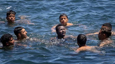 Moroccan migrants help an African fellow facing difficulties in the water at the border between Morocco and the Spanish enclave of Ceuta on May 19, 2021 in Fnideq. Spain stepped up diplomatic pressure on Rabat as its prime minister flew into Ceuta, vowing to restore order in the North African enclave after a record 8,000 migrants reached its beaches from Morocco.