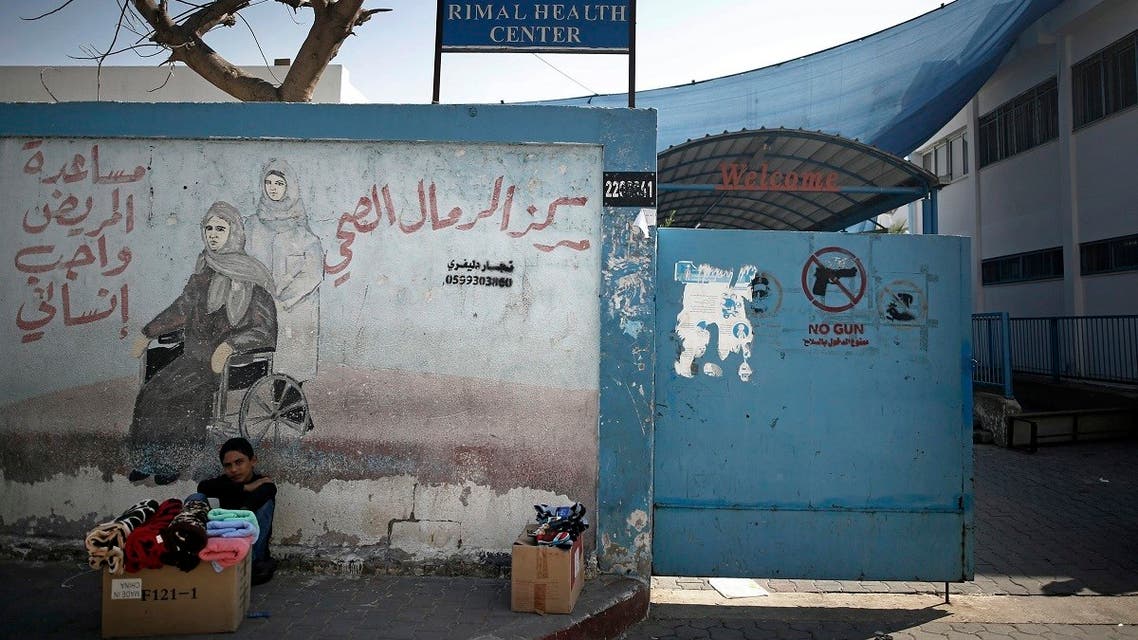 A Palestinian boy displays clothes for sale next to the entrance of the UNRWA Rimal Health Center in Gaza City. (File Photo: AP)