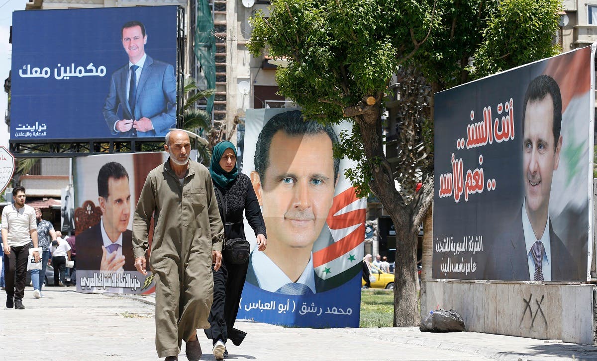 In this file photo taken on May 24, 2021, People walk next to election campaign billboards depicting Syrian President Bashar al-Assad, a candidate for the upcoming presidential vote, in the capital Damascus. (Louai Beshara/AFP)