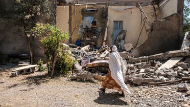 (FILES) In this file photograph taken on March 1, 2021, a woman walks in front of a damaged house in Wukro, north of Mekele which was shelled as federal-aligned forces entered the city. Eritrean soldiers are blocking and looting food aid in Ethiopia's war-hit Tigray region, according to government documents obtained on April 27, 2021, by AFP, stoking fears of starvation deaths as fighting nears the six-month mark.