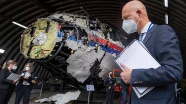 Presiding judge Hendrik Steenhuis (R) points as he and other trial judges and lawyers stand next to the reconstructed wreckage of Malaysia Airlines Flight MH17, at the Gilze-Rijen military airbase, southern Netherlands, on May 26, 2021. Judges inspect wreckage of flight MH17 as part of criminal trial of four suspects. (File photo: AFP)