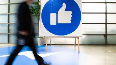 A Facebook employee walks by a sign displaying the like sign at Facebook's corporate headquarters campus in Menlo Park, California, on Oct. 23, 2019. (Reuters)