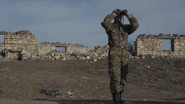 An ethnic Armenian soldier looks through binoculars as he stands at fighting positions near the village of Taghavard in the region of Nagorno-Karabakh, Jan. 11, 2021. (Reuters)
