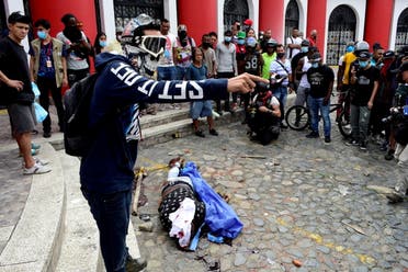 A demonstrator yells as he stands next to the body of an agent of the attorney general's investigative unit, who opened fire on civilians before being killed, as protests demanding government action to tackle poverty, police violence and inequalities in healthcare and education systems continue, in Cali, Colombia May 28, 2021. (Reuters)