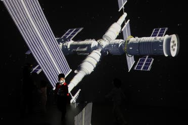 طفل يمشي في معرض في بكين امام صورة عملاقة لمحطة الفضاء الصينية