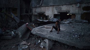 A boy closes his eyes as he plays hide-and-seek at dusk in a neighborhood heavily damaged by airstrikes during an 11-day war between Gaza's Hamas rulers and Israel, Monday, May 31, 2021 in Beit Hanoun, Gaza Strip. (AP)