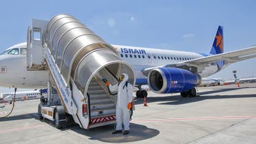 An Israeli worker in full hazmat suit sprays disinfectant on the boarding stairs of an Israir Airlines Airbus A320 airplane, at the Ben Gurion International Airport near the central Israeli city of Tel Aviv. (File photo: AFP)