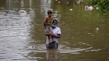 A Sri Lankan man wades through in an inundated street carrying a child following heavy rainfall at Malwana, on the outskirts of Colombo, Sri Lanka, June 5, 2021 (AP/Eranga Jayawardena)
