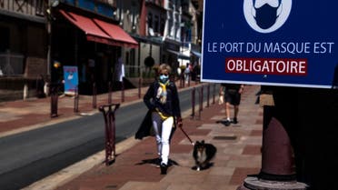 A woman walks past a sign indicating Face masks mandatory, in Houlgate, north-western France, on June 5, 2021. (Joel Saget/AFP)