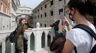Tourists take pictures on a bridge as Italy lifts quarantine restrictions for travellers arriving from European Union countries, Britain and Israel and begins offering COVID-free flights in a bid to revive the tourism industry, in Venice, Italy, May 16, 2021. (Reuters)