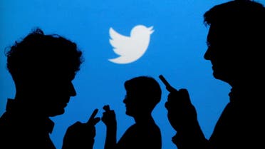 People holding mobile phones are silhouetted against a backdrop projected with the Twitter logo. (File Photo: Reuters)