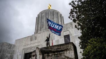 A far-right protester waves a Trump flag in front of the Capitol building during a protest against restrictions to prevent the spread of coronavirus disease (COVID-19) in Salem, Oregon, U.S., December 21, 2020. REUTERS/Mathieu Lewis-Rolland TPX IMAGES OF THE DAY
