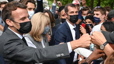 French President Emmanuel Macron (L) and his wife Brigitte Macron (C) interact with members of a crowd while visiting Valence on June 8, 2021 during a visit in the French southeastern department of Drôme, the second stage of a nationwide tour ahead of next year's presidential election. (AFP)